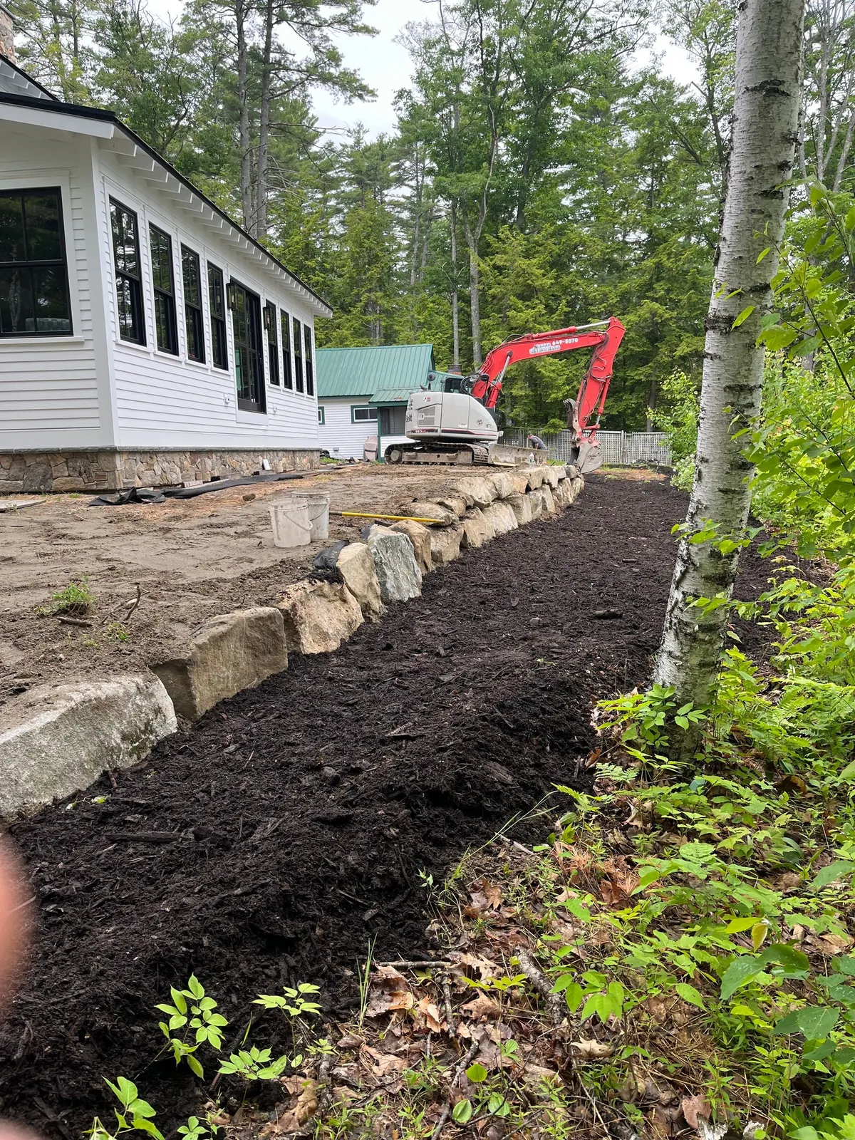 Excavation work in progress on a wooded Maine lot.