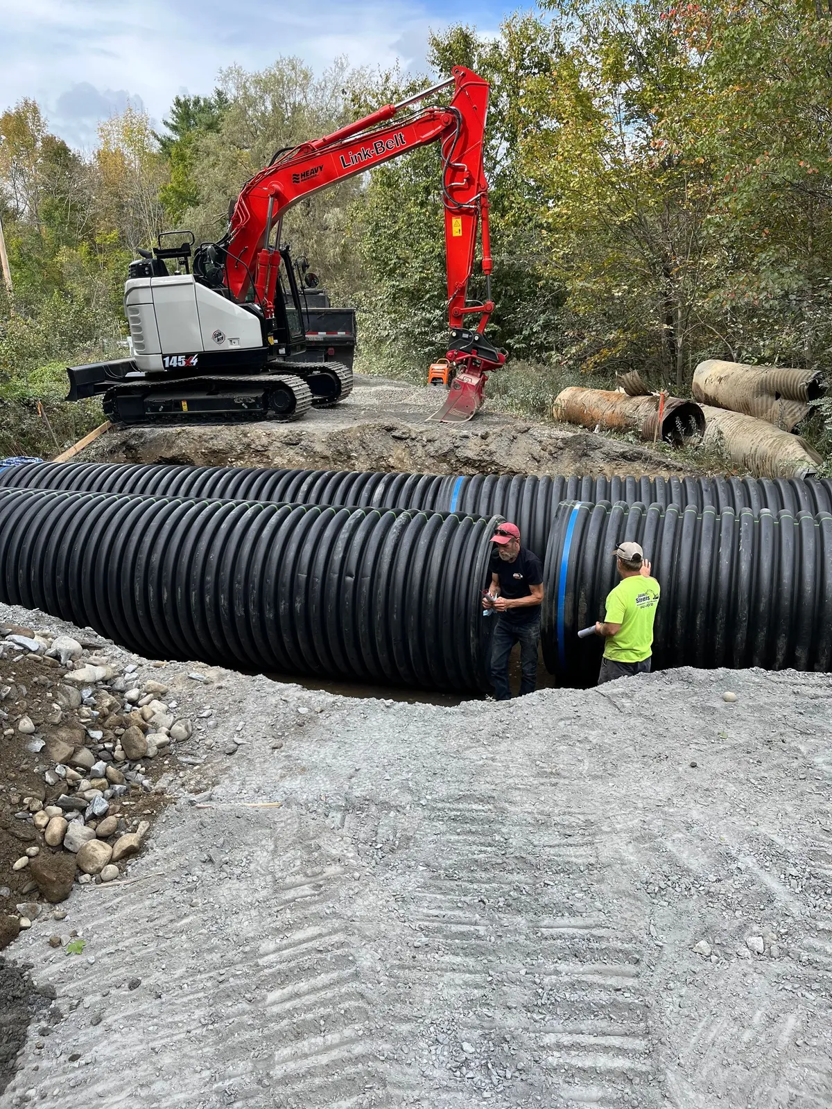 A culvert pipe set beneath a gravel driveway crossing.